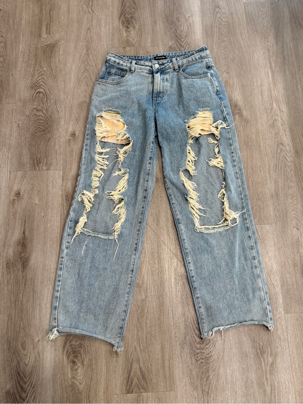 Distressed blue denim jeans with ripped knees and frayed hem